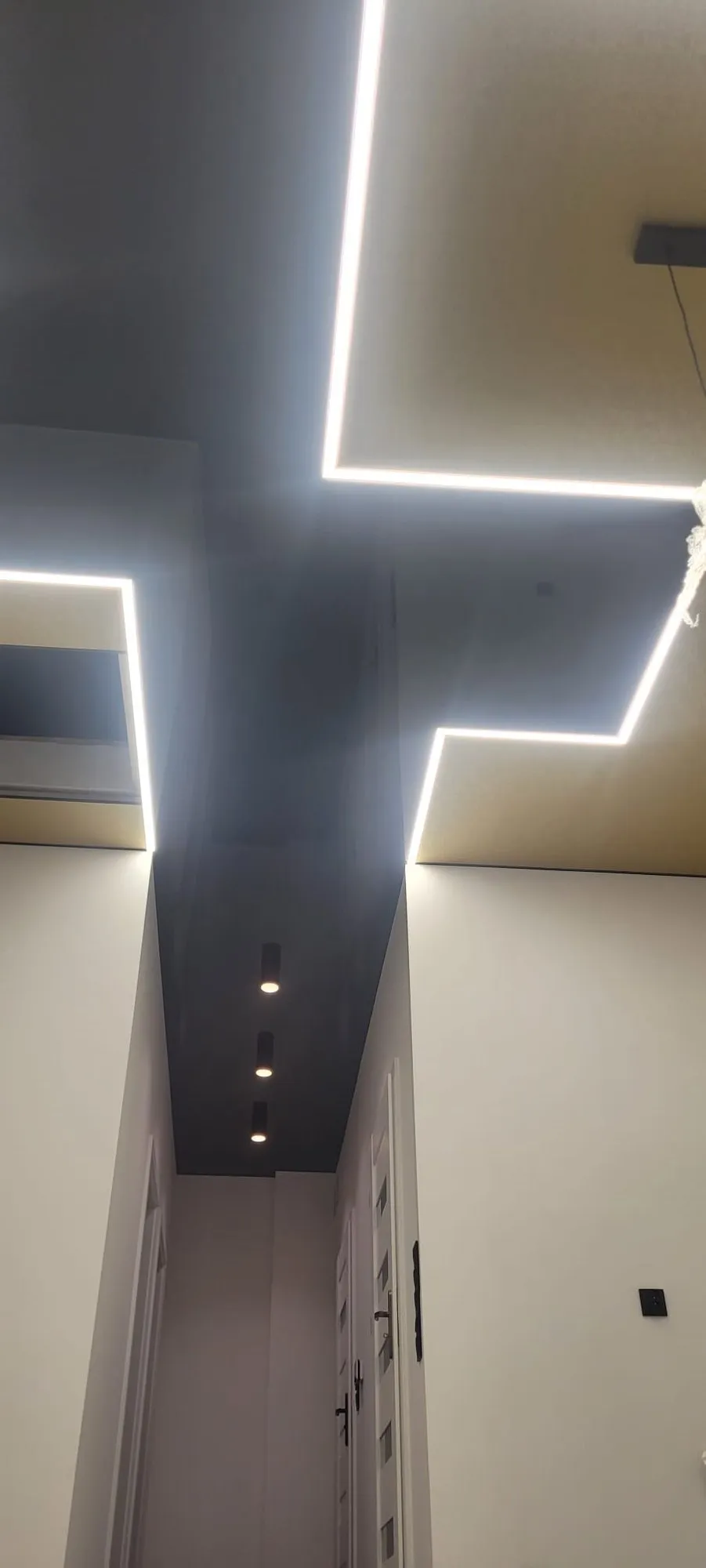 Czarny sufit z krzyżem z linii LED w korytarzu